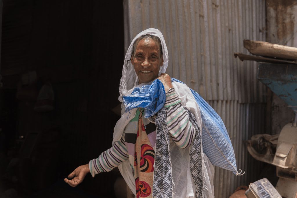 A woman carrying a bag of rice.